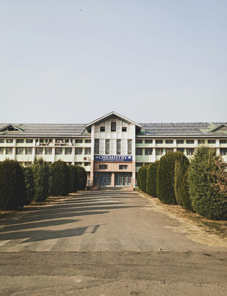 Front view of a modern building with a Chemistry department sign surrounded by greenery.